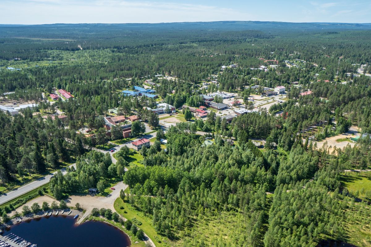 Ilmakuva Hyrynsalmen keksustasta: vesistöä, venesatama, rakennuksia ja metsää.