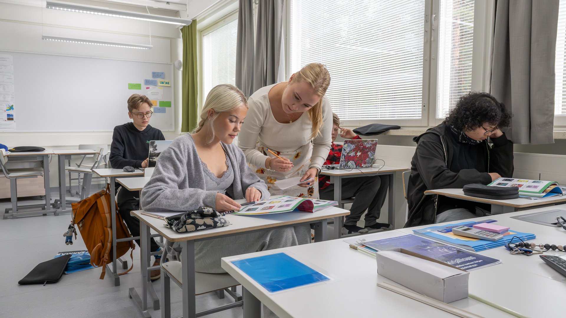 Kuvassa naisopettaja näyttää jotain oppilaalle kirjasta