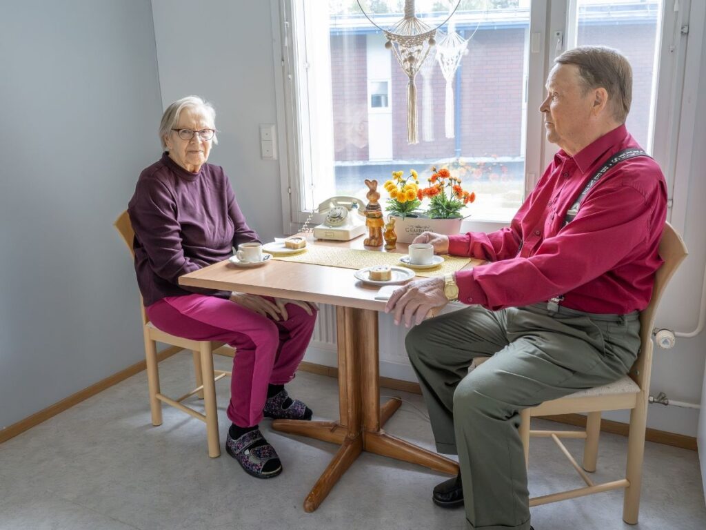 Vanha nainen ja mies istuvat pöydän ääressä