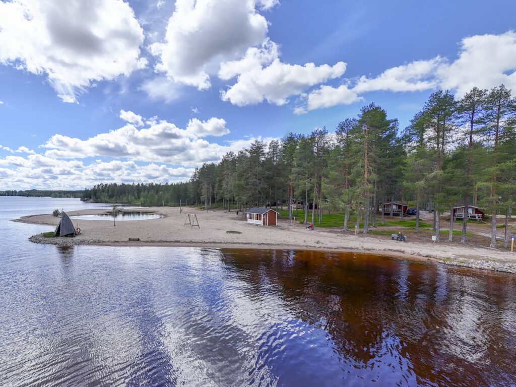 Kuva Camping Vonkan rannalta. Kuvassa hiekkarantaa ja camping mökkejä